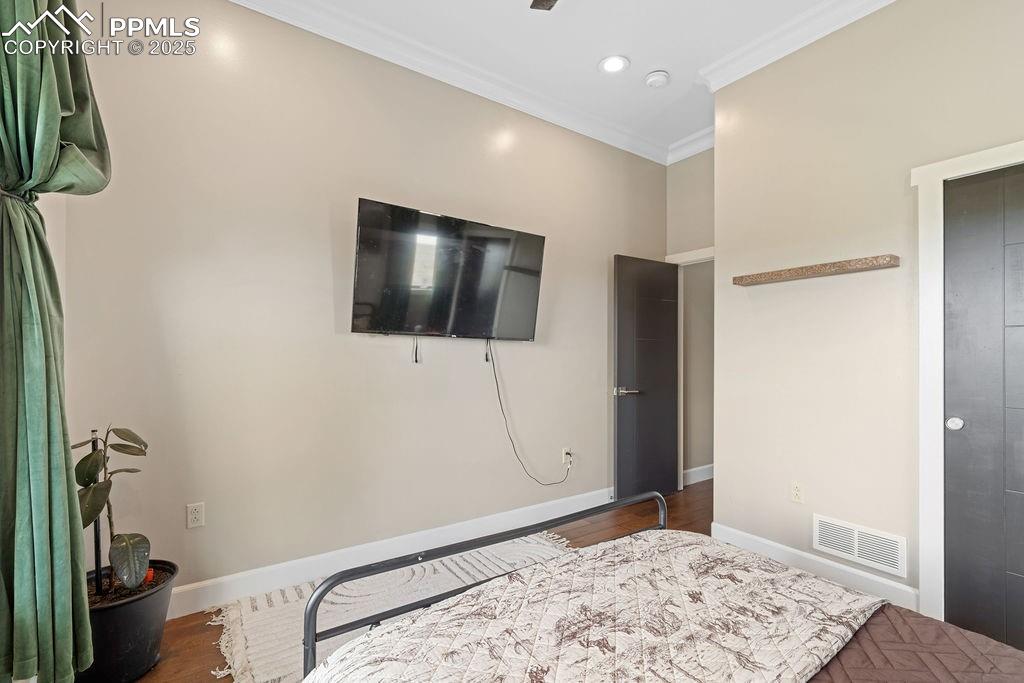 Image 42 of 50: Bedroom with crown molding, wood finished floors, and recessed lighting