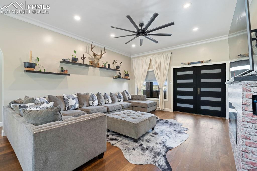 Image 8 of 50: Living room with crown molding, wood finished floors, recessed lighting, an