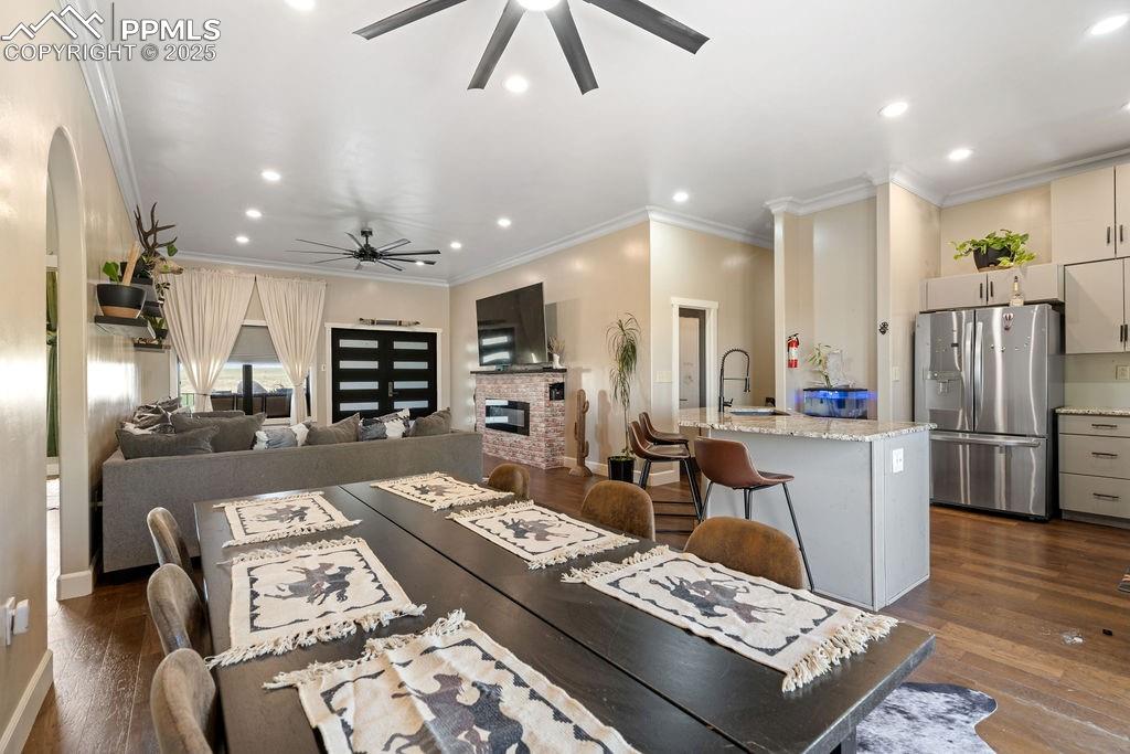 Image 9 of 50: Living area with wood finished floors, ornamental molding, ceiling fan, a f