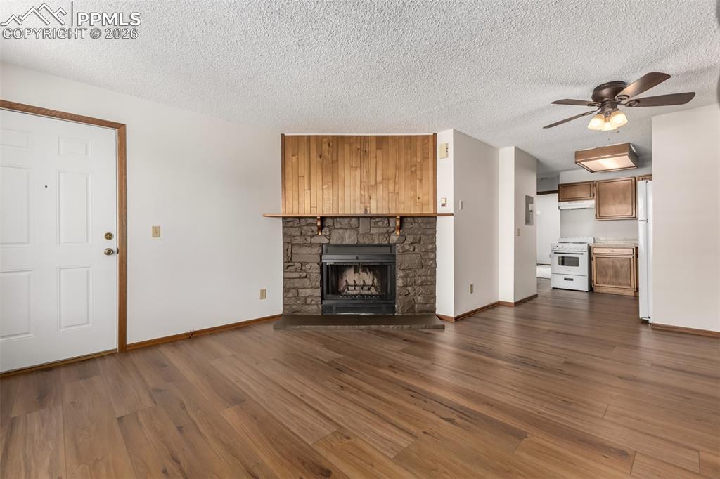 Image 5 of 25: Bright living room with large window and inviting fireplace focal point.
