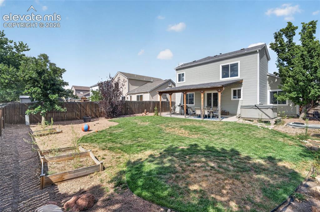 Image 21 of 30: Fully fenced backyard with raised garden beds