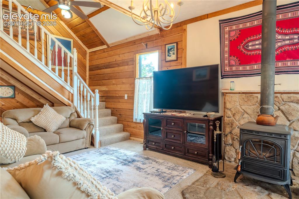 Image 10 of 40: Living area featuring a floor-to-ceiling wood plank accent wall, a stone he