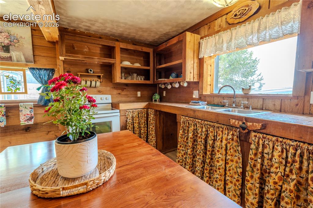 Image 14 of 40: Kitchen featuring wood plank walls, exposed wood beams, wood-finish floorin