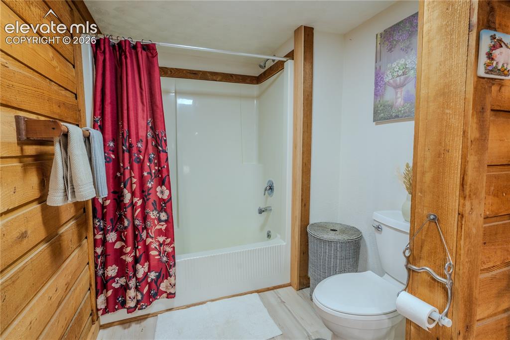 Image 19 of 40: Bathroom featuring a white tub/shower combination, white toilet, and wood-f