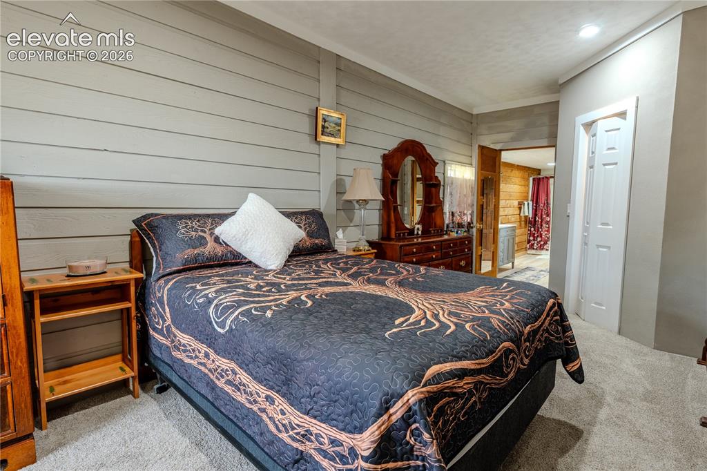 Image 21 of 40: Bedroom featuring horizontal plank wall paneling and neutral-toned carpetin