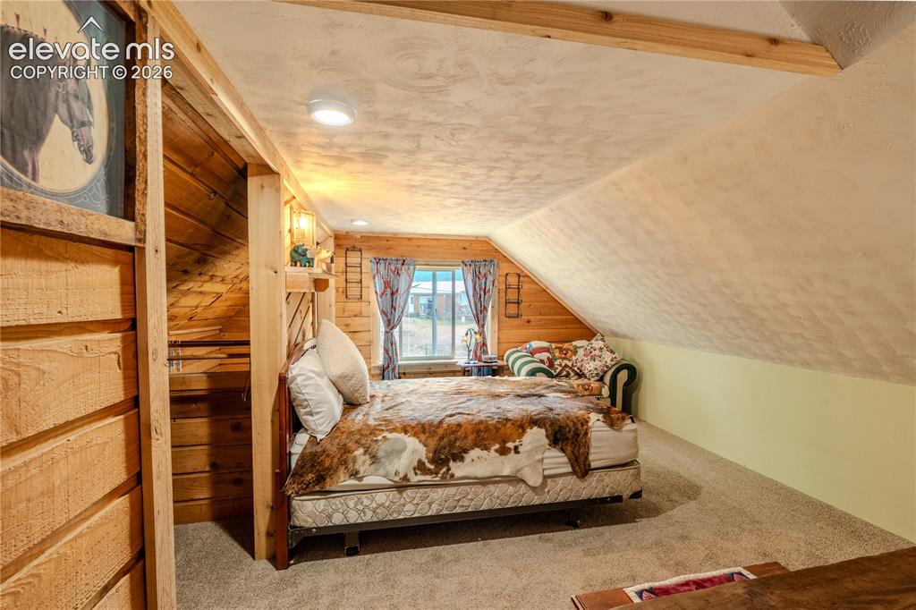 Image 24 of 40: Wood-paneled room featuring sloped ceilings, a window, and recessed lightin