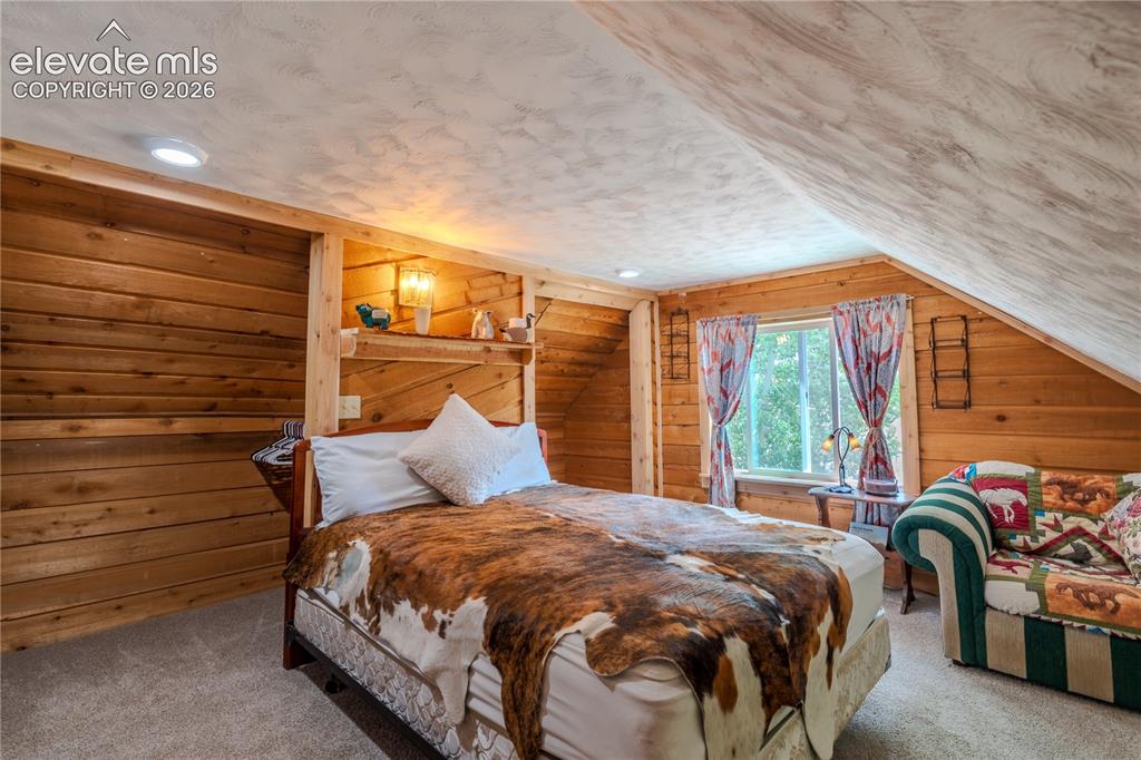 Image 25 of 40: Bedroom featuring wood plank walls, built-in shelving, recessed lighting, a