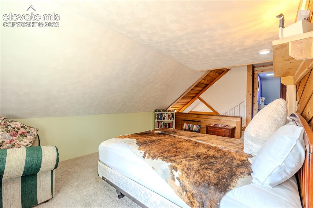 Image 26 of 40: Carpeted room with a sloped ceiling and light green painted walls