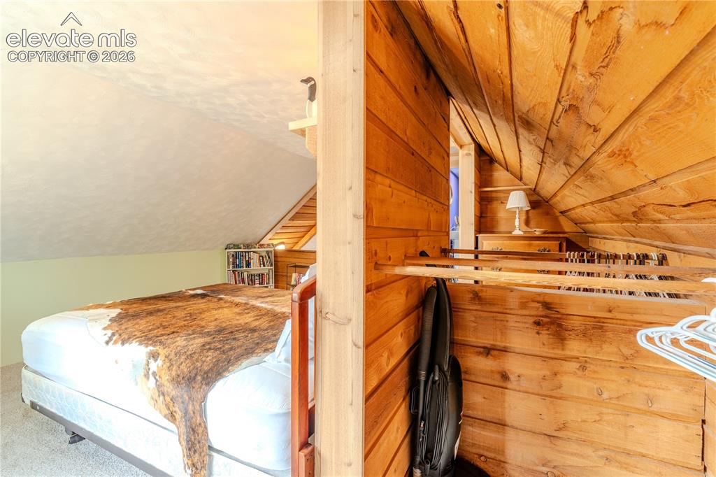 Image 27 of 40: Sloped ceiling room featuring a built-in bookshelf, light-colored walls, an