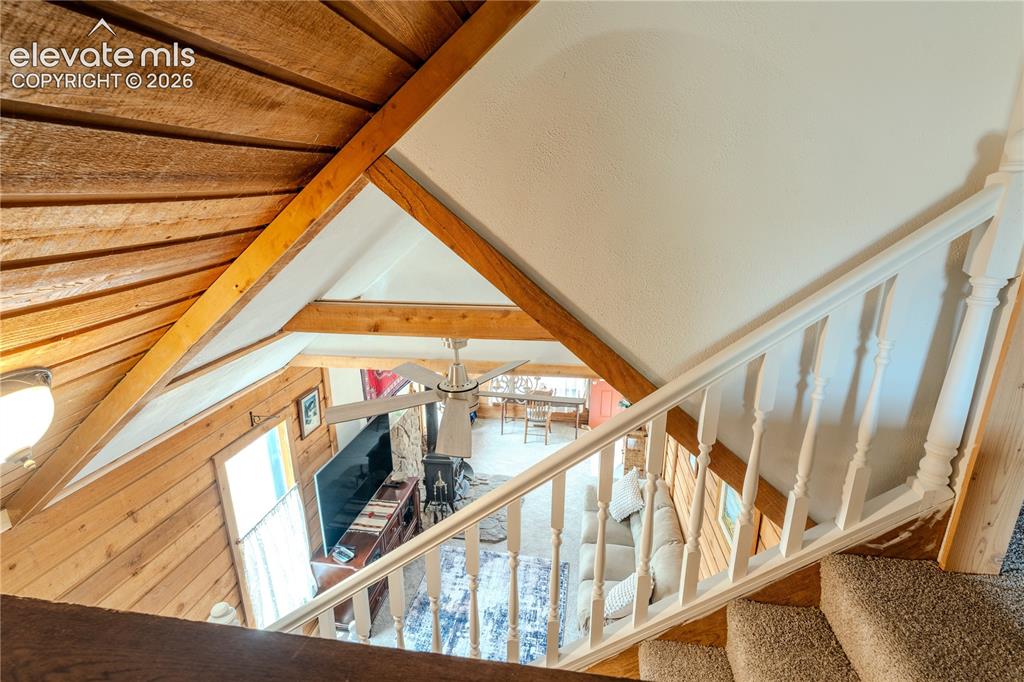 Image 29 of 40: Carpeted staircase with white baluster railing overlooking a living space f