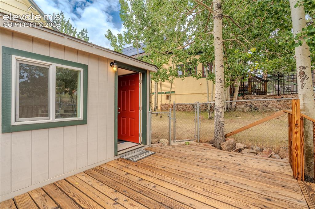 Image 33 of 40: Exterior building with vertical siding and a vibrant red entry door