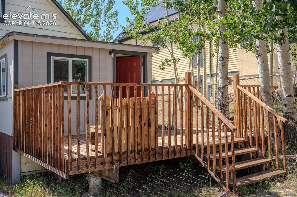 Image 35 of 40: Exterior wood deck with railings and steps, featuring a red entry door and