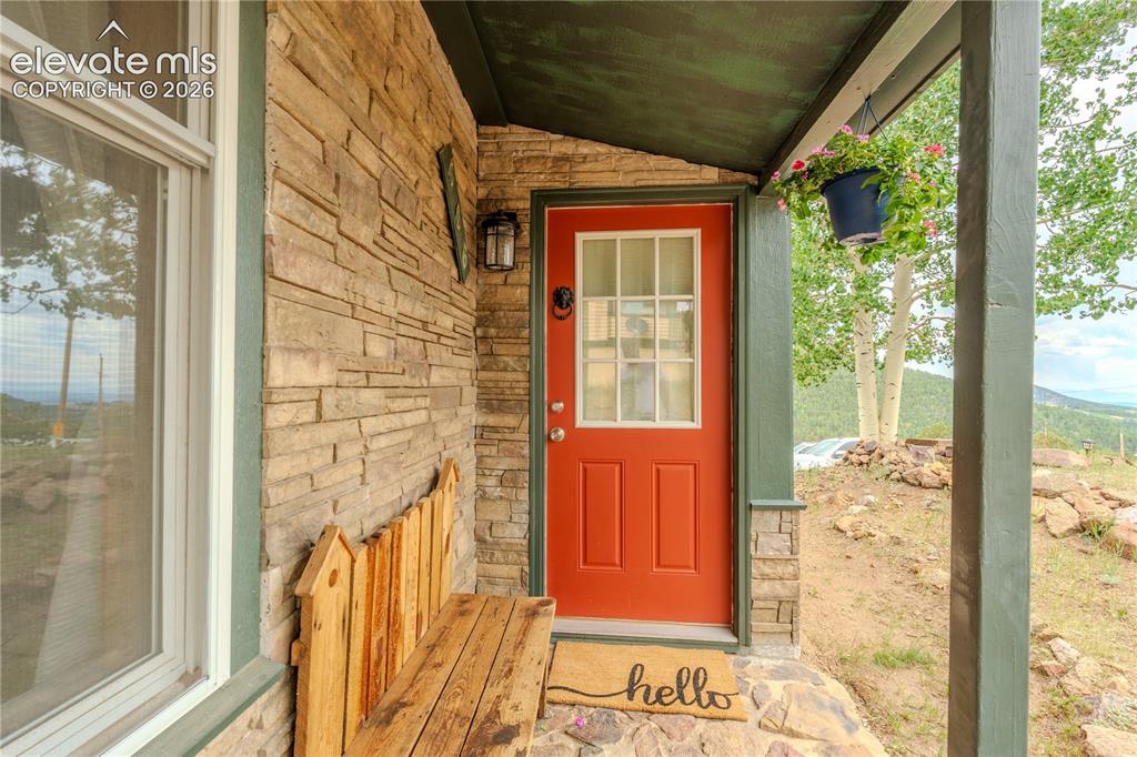 Image 4 of 40: Stone veneer exterior featuring an orange panel door with window inserts, a