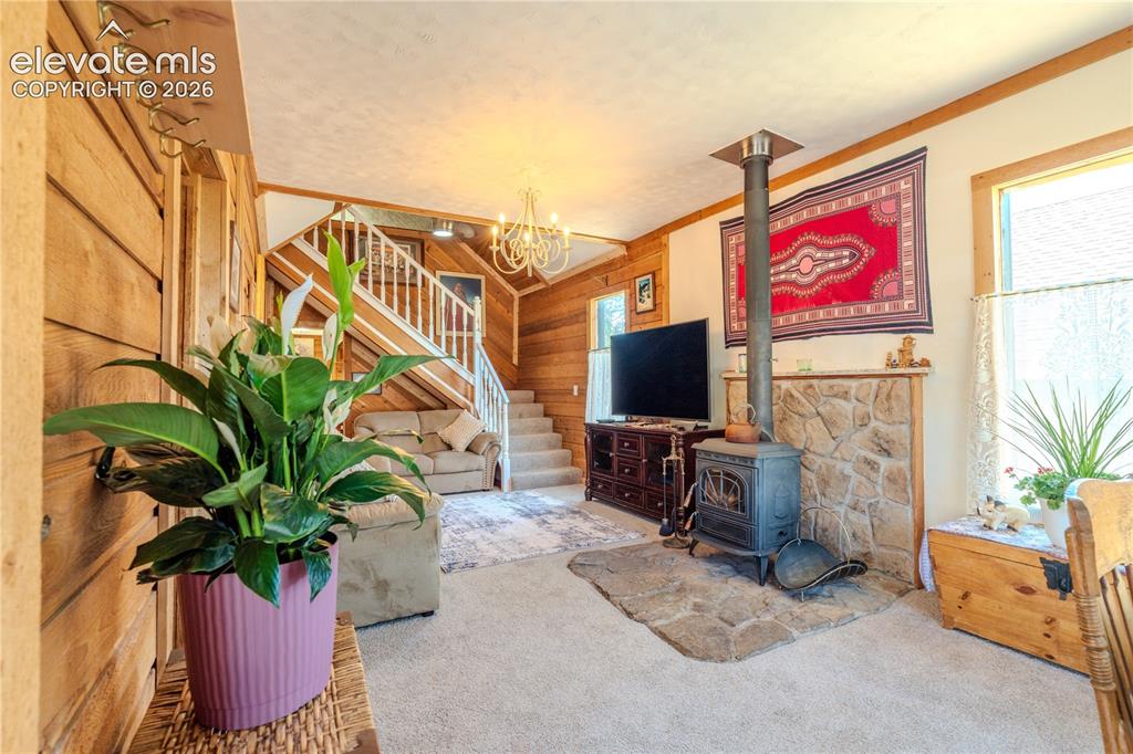 Image 7 of 40: Living room featuring wood-paneled walls and a built-in staircase with whit