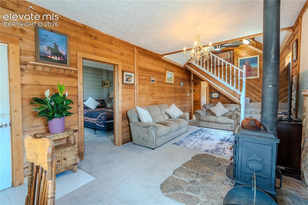 Image 8 of 40: Living area featuring wood-paneled walls, carpet flooring, and a visible st