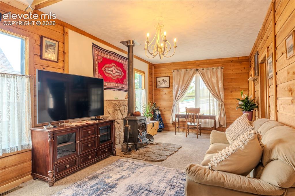 Image 9 of 40: Living area featuring extensive wood paneling and exposed ceiling beams