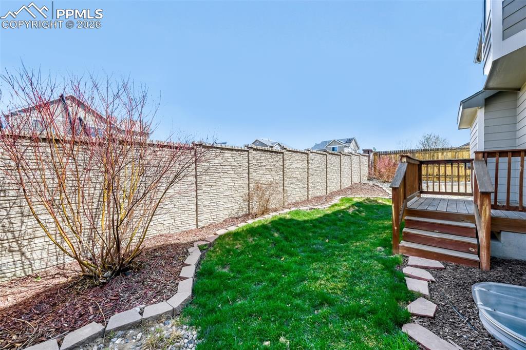 Image 25 of 28: Rear view of house featuring a fenced backyard and a wooden deck