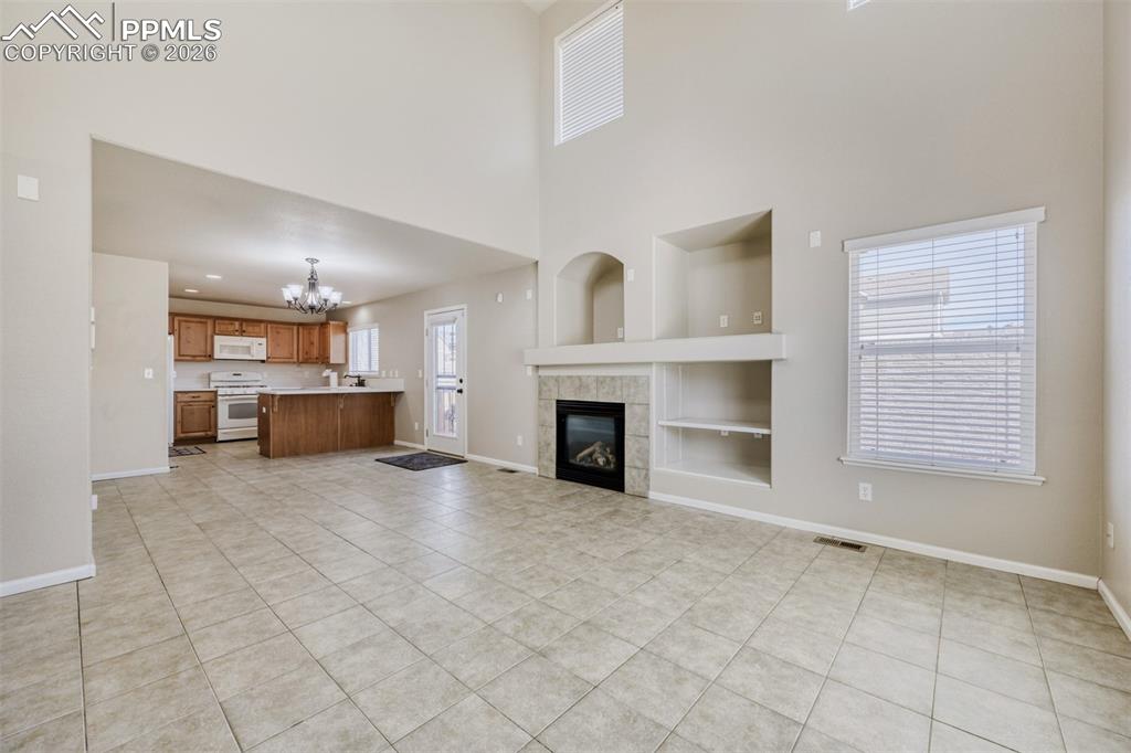 Image 4 of 28: Dining and Great room featuring tile floors, a fireplace, built in entertai