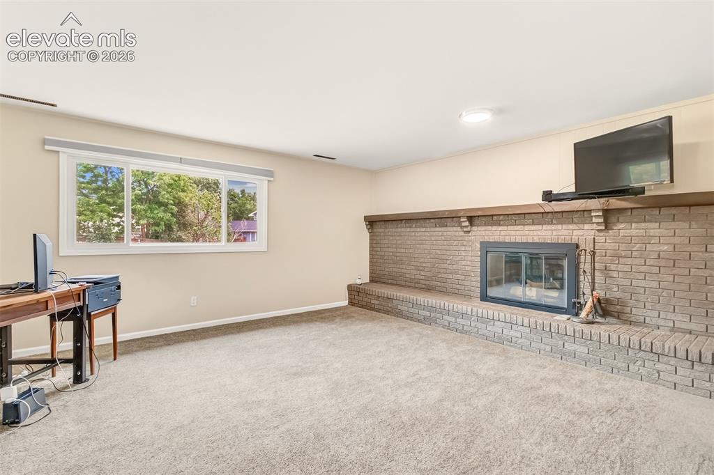 Image 21 of 39: Family room with wood burning fireplace on lower level