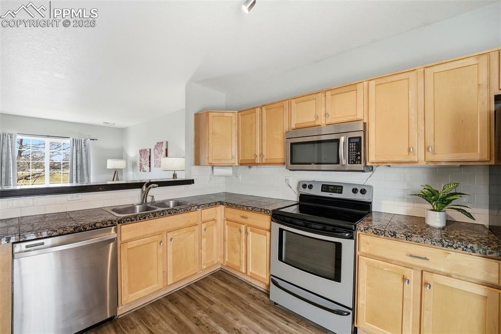 Image 10 of 44: Kitchen featuring wood-finish cabinetry, dark speckled countertops, stainle