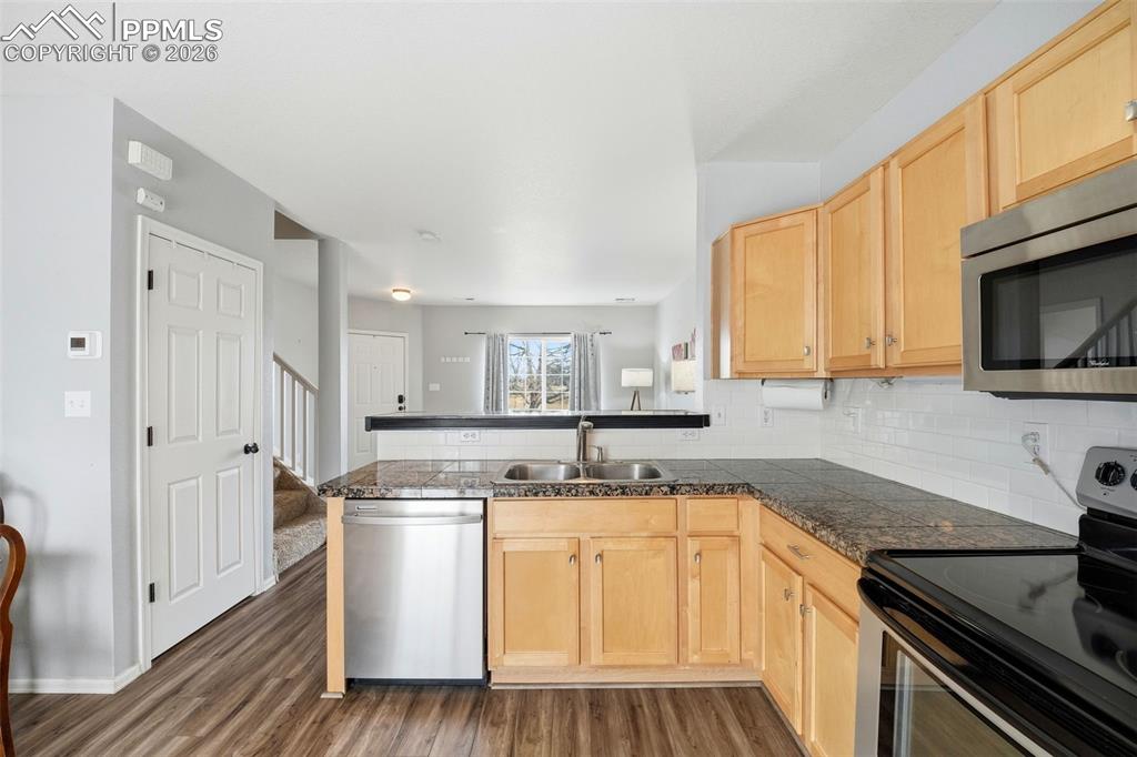 Image 11 of 44: Kitchen featuring wood-finish flooring, granite countertops, light wood cab