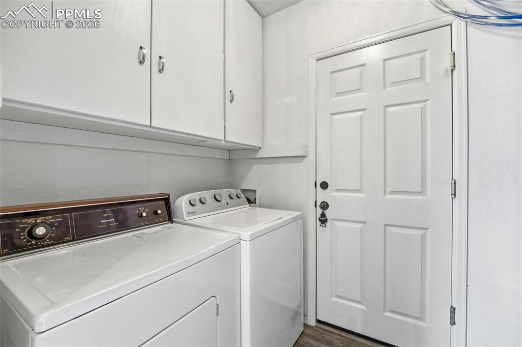 Image 14 of 44: Laundry area featuring built-in white cabinetry, paneled door, and wood-fin