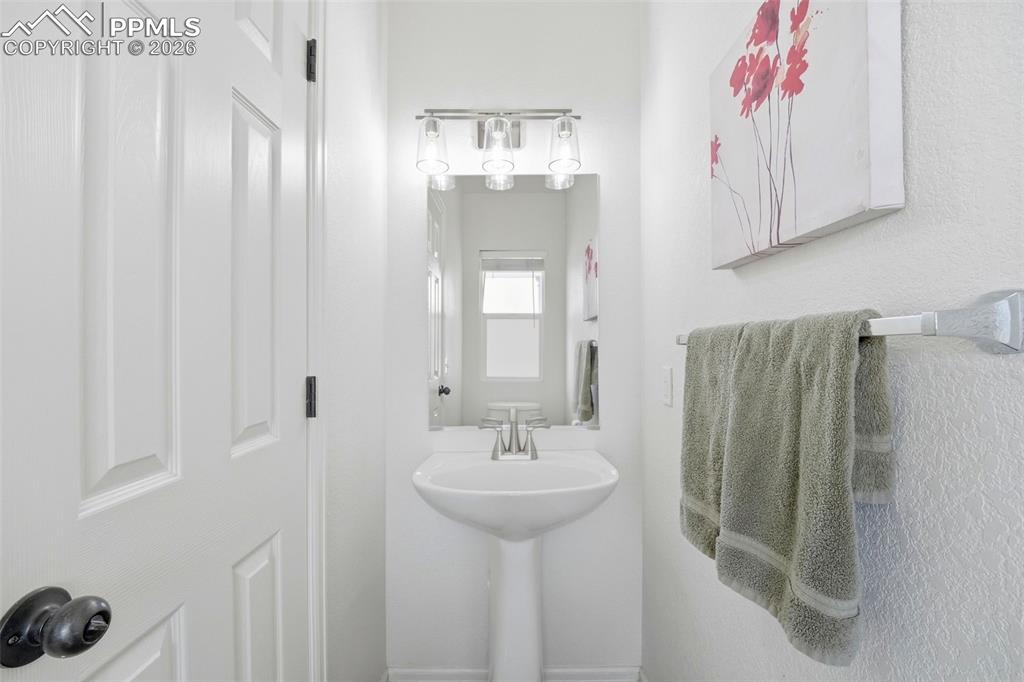 Image 15 of 44: Pedestal sink with chrome faucet, overhead vanity lighting, and a wall-moun