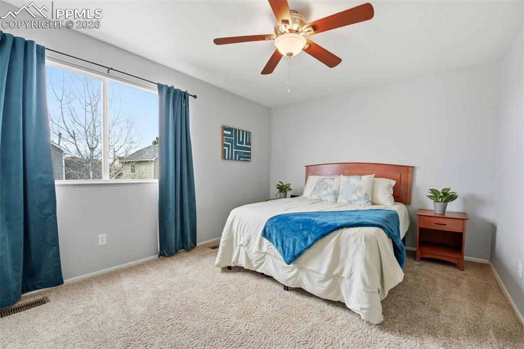 Image 16 of 44: Carpeted bedroom featuring a large window, a ceiling fan with light fixture