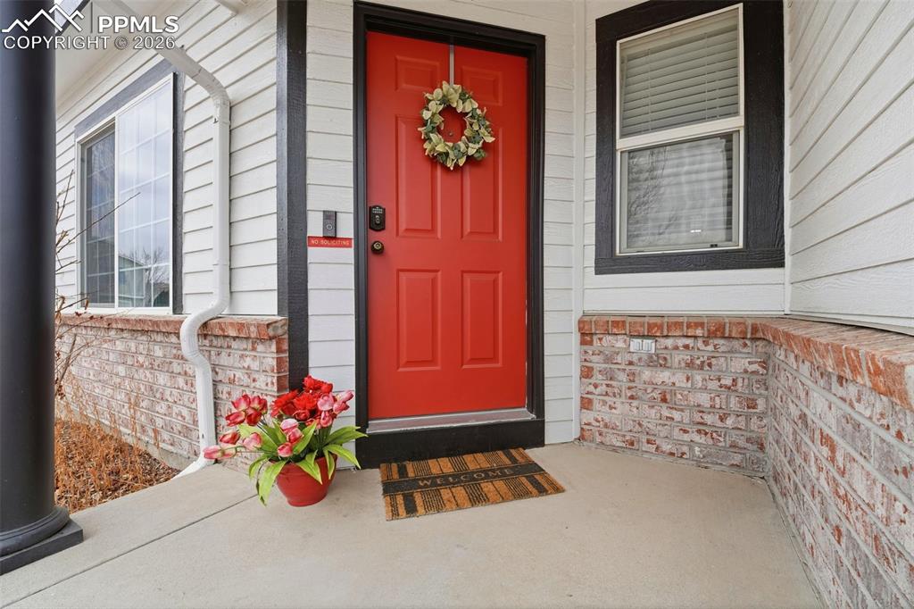 Image 2 of 44: Inviting entryway featuring a vibrant red paneled door with a digital keypa