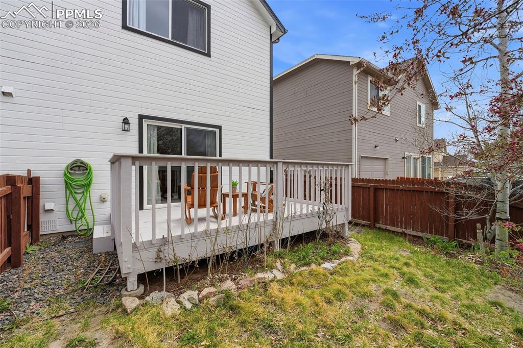 Image 28 of 44: Rear deck with white railings and a sliding glass door entry