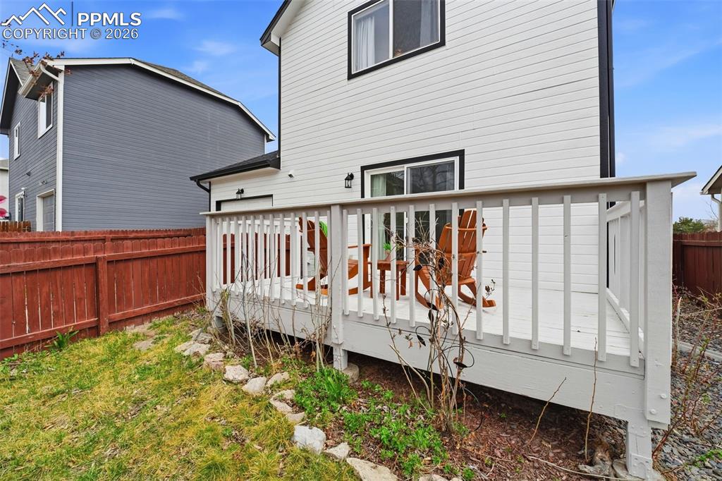 Image 29 of 44: Ground-level deck with white painted railings and a sliding glass door entr