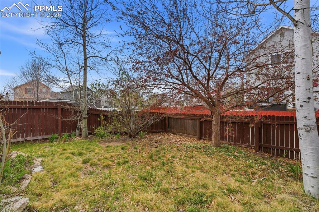 Image 30 of 44: Fenced backyard featuring mature trees and a grass lawn