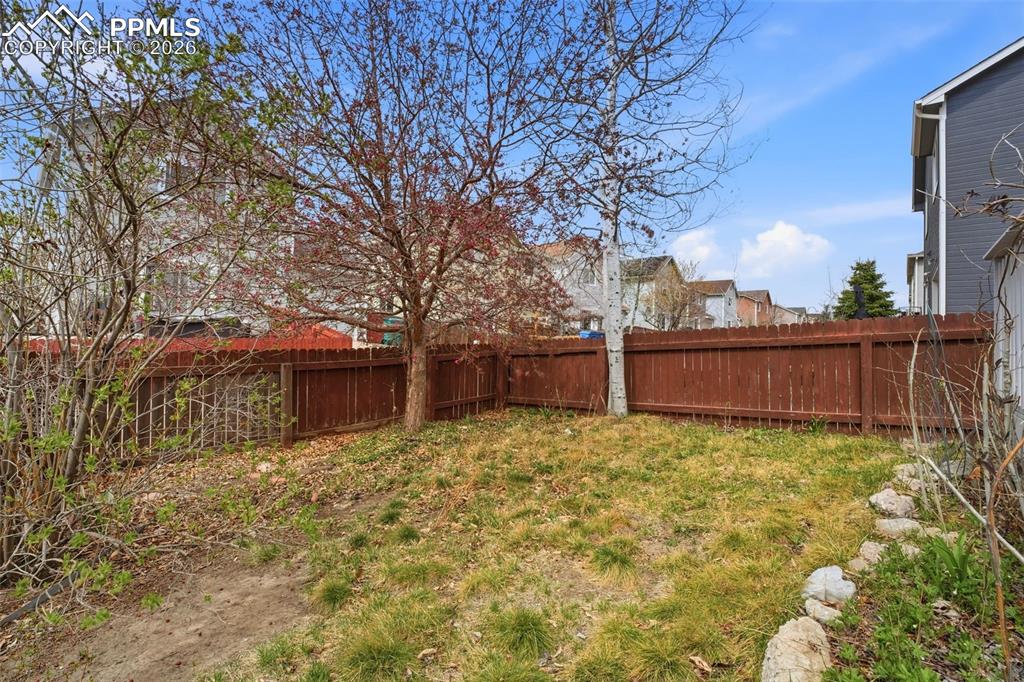 Image 31 of 44: Private backyard featuring a full wooden privacy fence, mature trees, and n