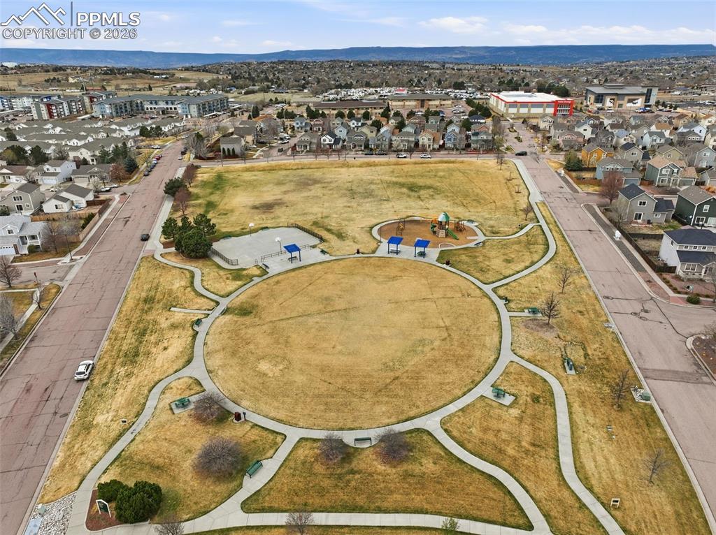 Image 35 of 44: Expansive park area featuring a circular central lawn, a playground structu