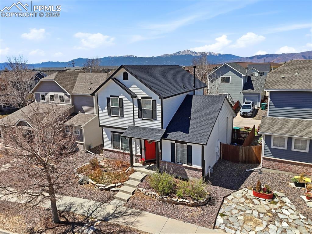 Image 38 of 44: Two-story residence featuring white siding, dark shutters, and a red entry 
