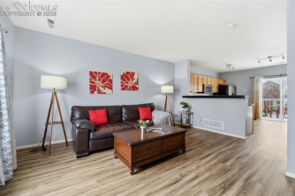 Image 4 of 44: Spacious living area featuring wood-finish flooring, light gray walls, and 