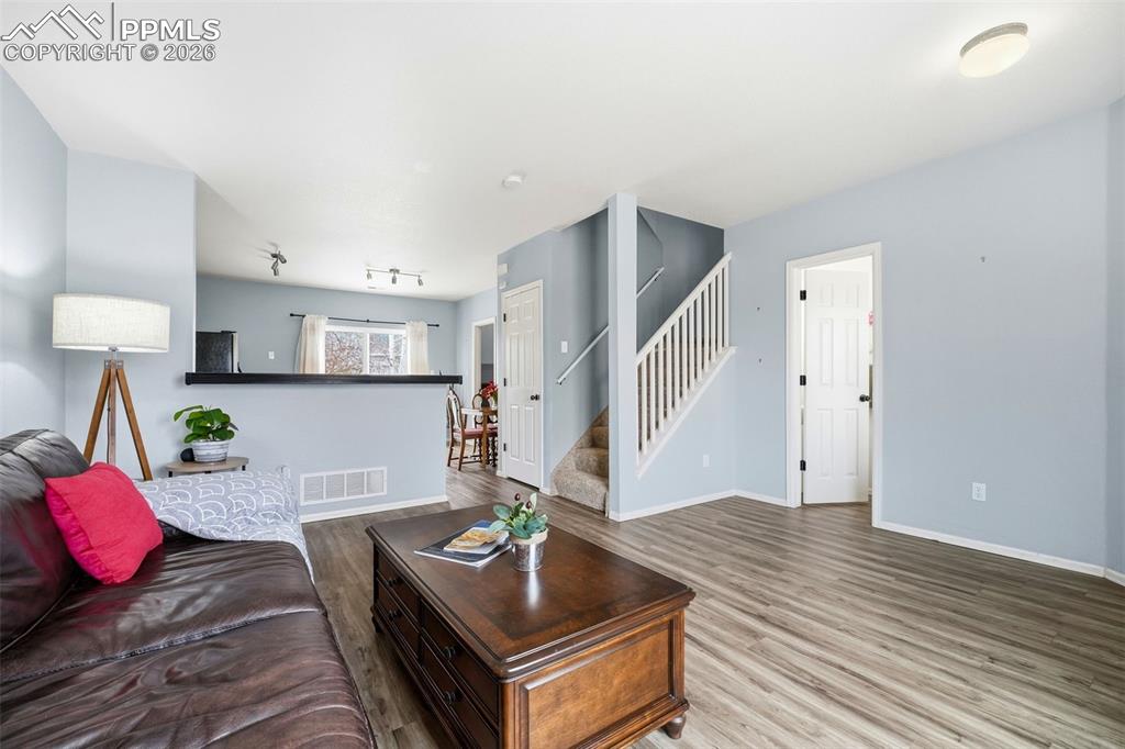 Image 5 of 44: Open-concept living area featuring wood-finish flooring, a staircase with w