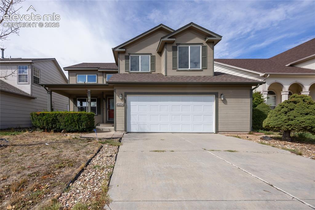 Caption: Two-story exterior with a covered porch, attached two-car garage, and concrete driveway