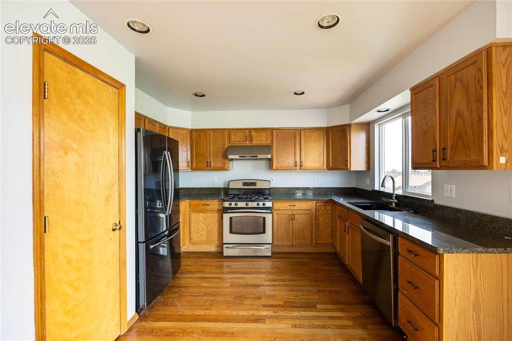 Image 10 of 34: Kitchen featuring wood-finish flooring, recessed lighting, wood cabinetry,