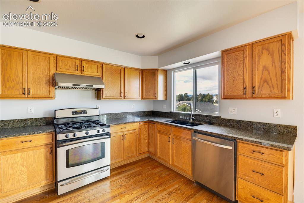 Image 11 of 34: Kitchen featuring wood cabinetry, dark countertops, stainless steel applian