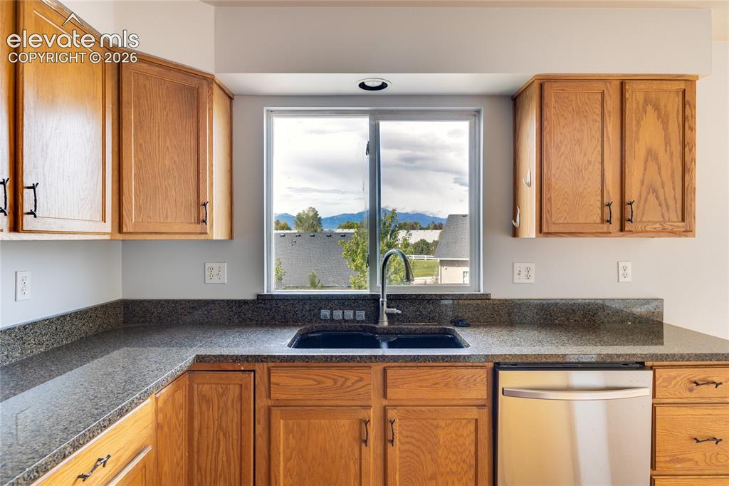 Image 12 of 34: Kitchen featuring extensive wood cabinetry, dark speckled countertops, a do