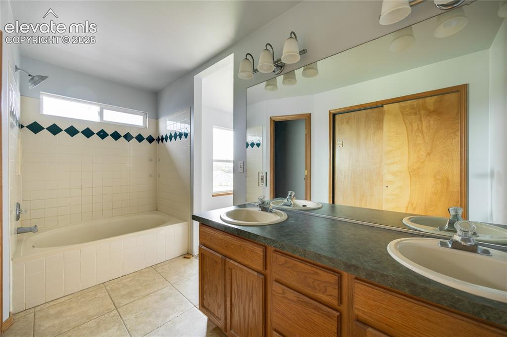 Image 18 of 34: Dual vanity with integrated sinks, wood-finish cabinetry, full-width mirror