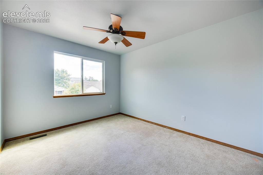 Image 19 of 34: Light gray wall paint, light-colored carpet flooring, a window with wood-fi