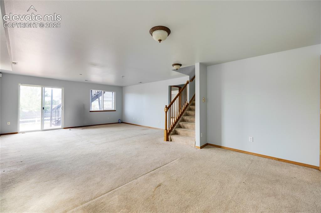 Image 24 of 34: Spacious room featuring carpeting, a sliding glass door, a window, a wooden