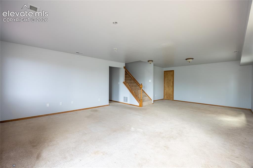 Image 25 of 34: Expansive carpeted area with neutral wall tones and recessed lighting