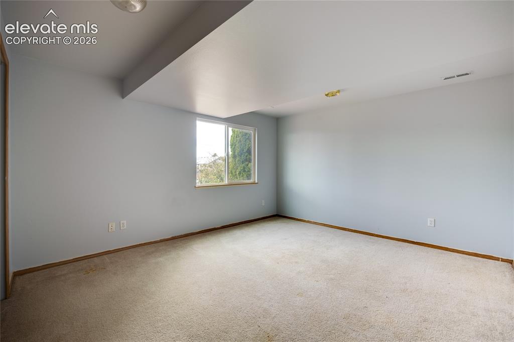 Image 26 of 34: Expansive room with neutral carpeting and light-toned walls