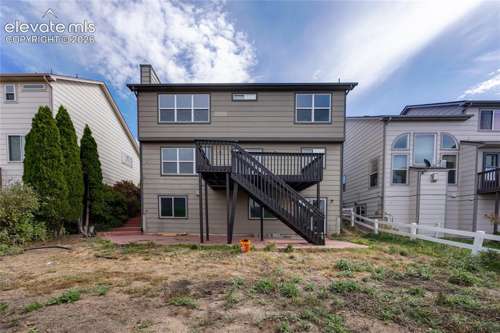 Image 30 of 34: Two-story exterior with a ground-level patio and an elevated deck with stai