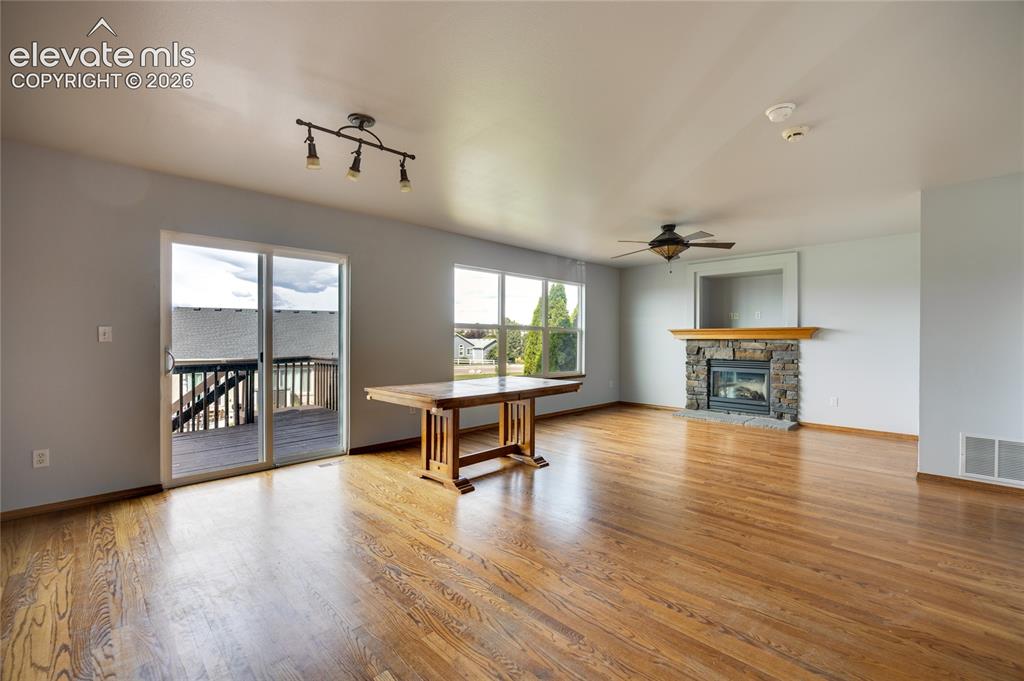 Image 6 of 34: Hardwood flooring, sliding glass door to exterior deck, stone fireplace wit