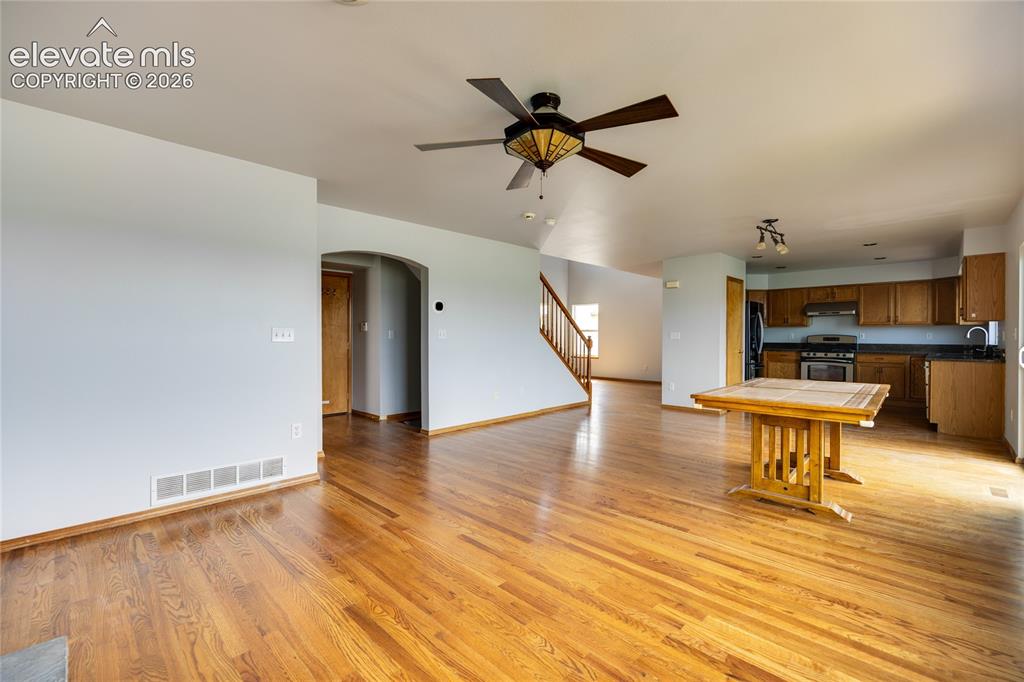 Image 8 of 34: Open-concept living space with wood-finish flooring, a ceiling fan with int