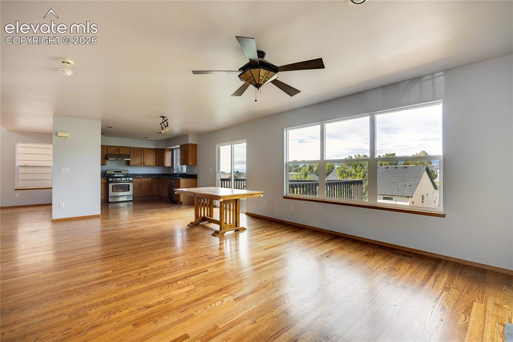 Image 9 of 34: Open-concept living area featuring wood-finish flooring, a ceiling fan with